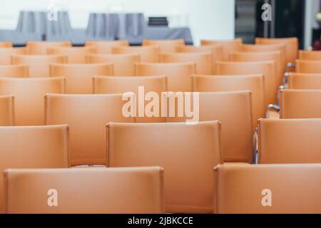 grande sala conferenze vuota con sedie arancioni prima dell'asta Foto Stock