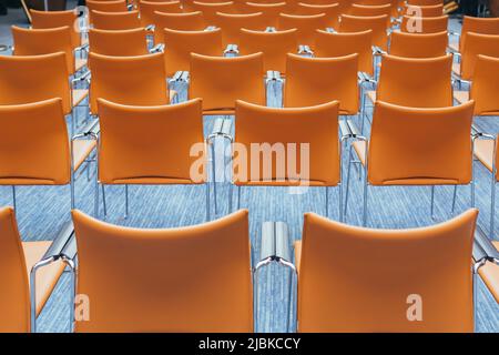 grande sala conferenze vuota con sedie arancioni prima dell'asta Foto Stock
