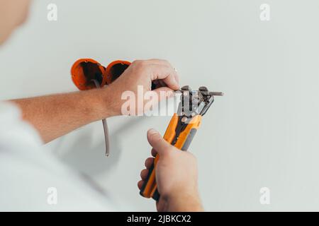 Un elettricista professionista uomo monta una presa elettrica nell'appartamento dopo la riparazione, foto ravvicinata dell'installatore Foto Stock