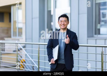 Ritratto bell'uomo asiatico un insegnante universitario, uomo d'affari, scienziato o educatore. Sede in piedi moderno ufficio o campus con Foto Stock