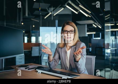 Donna seria e arrabbiata che guarda la webcam, parla di collegamento video, conferenza online incontro con i colleghi, donna d'affari che lavora da un ufficio moderno Foto Stock