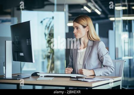 Una donna d'affari arrabbiata e arrabbiata guarda lo schermo del computer, insoddisfatta dei risultati dei test statistici, lavora in ufficio Foto Stock