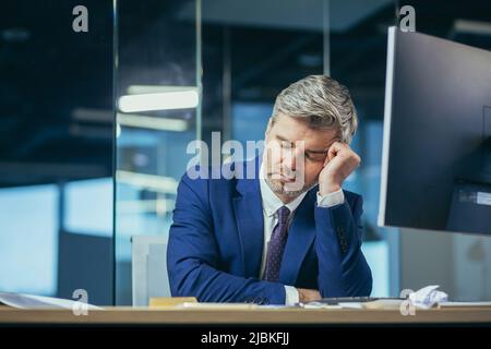Uomo d'affari con capo anziano stanco che dorme sul desktop in ufficio Foto Stock