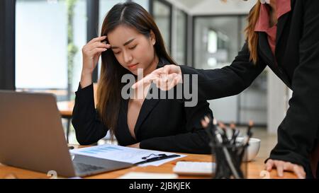 Una donna d'affari asiatica stressata e sconvolsa o una dipendente di ufficio femminile riceve una cattiva denuncia e un'opinione dal suo capo. Foto Stock