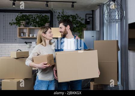 Felice coppia uomo e donna vivono insieme, si sono trasferiti in un nuovo appartamento affittato, tenendo scatole di cartone Foto Stock