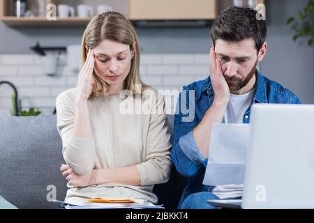 L'uomo e la donna, la giovane famiglia insieme intentemente leggendo una lettera, frustrati Foto Stock