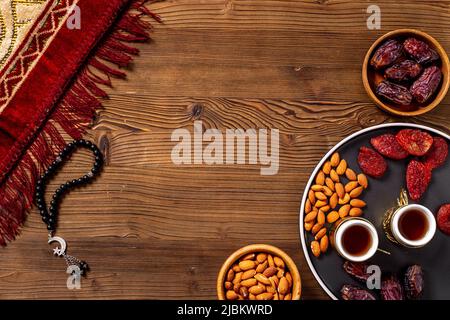 Concetto di Ramadan Kareem. Tappeto di preghiera islamico con rosario e frutta secca Foto Stock