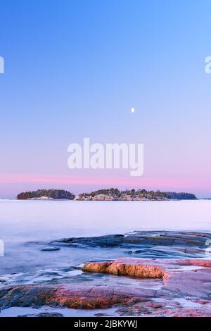 Luna sopra un'isola vicino Helsinki durante l'alba Foto Stock