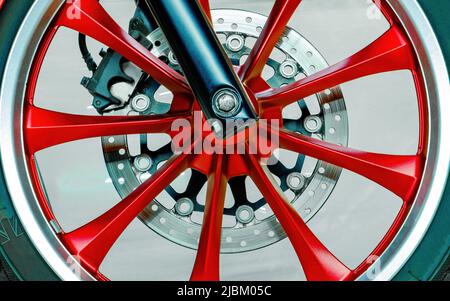 Ruota della moto moderna. Raggi, disco freno, pastiglie. Primo piano. Colore rosso, nero, cromo Foto Stock