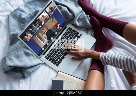 Giovane donna freelance video chattare con i colleghi mentre lavora a letto a casa. Inalterato, online, tecnologia, video conferenza, discussione, inte Foto Stock