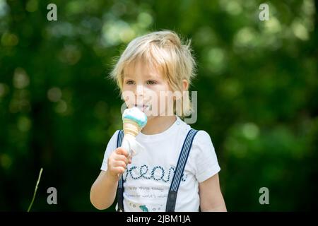 Bambino, ragazzo carino, mangiare gelato nel parco, all'aperto Foto Stock