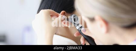Primo piano di otolaringologo femminile che esamina l'orecchio con Foto Stock