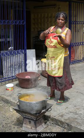 COSTA D'AVORIO, Abidjan, cucina scolastica, cuoca donna con grembiule da cucina Maggi pubblicità della società svizzera Nestle / ELFENBEINKUESTE, Abidjan, Stadtteil Koumassi-Remblais, Schulküche, Köchin in Schürze mit Maggi Werbung des Schweizer Konzern Nestle Foto Stock