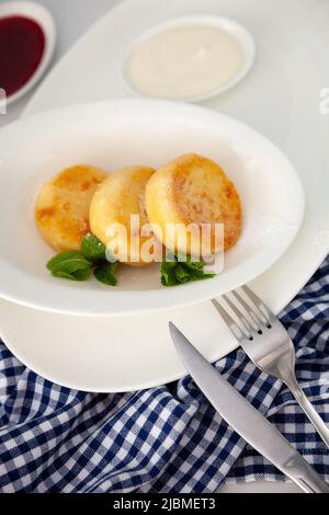 Una porzione di tre pancake rotondi di formaggio cagliato su un piatto bianco. Colazione sana. Sfondo alimentare. Spazio di copia. Foto Stock