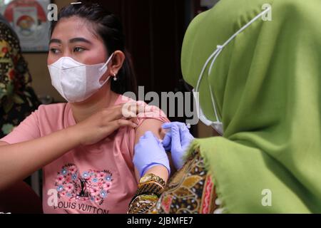 Surakarta, Indonesia. 7th giugno 2022. Un operatore sanitario inocula una donna con una dose di richiamo del vaccino COVID-19 a Surakarta, Giava centrale, Indonesia, 7 giugno 2022. Credit: Bram Selo/Xinhua/Alamy Live News Foto Stock