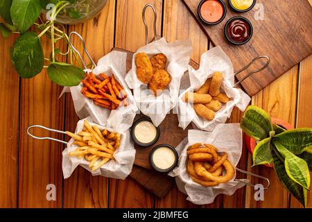 Un tavolo con molti snack fritti e salse Foto Stock