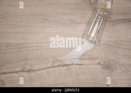 Vetro di acqua caduto su laminato, acqua versato sul pavimento. Foto Stock