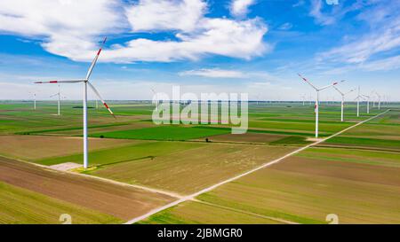 Sopra la vista sulla fattoria di grandi turbine eoliche sono in piedi tra i campi agricoli, generando energia elettrica pulita e verde rinnovabile. Foto Stock