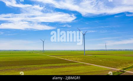 Sopra la vista sulla fattoria di grandi turbine eoliche sono in piedi tra i campi agricoli, generando energia elettrica pulita e verde rinnovabile. Foto Stock