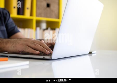 Utilizzando un computer portatile, immagine ravvicinata delle mani maschili utilizzando un computer portatile. Digitazione con le mani sulla tastiera del computer portatile. Lavorare o navigare su Internet in ufficio. Foto Stock