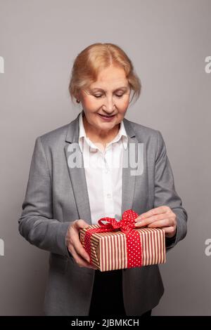 Senior business donna aprire rosso scatola regalo ritratto Foto Stock