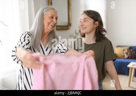 Ragazza adolescente stirare e aiutare con la famiglia chores sua nonna anziana a casa Foto Stock