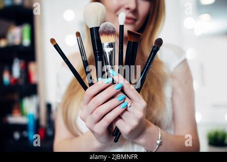 Immagine ravvicinata delle mani femminili che reggono un set di spazzole per il make-up. Foto Stock