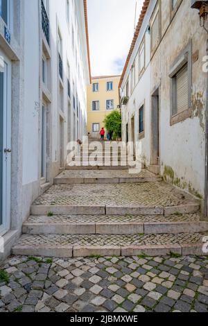 Un'attraente strada acciottolata si trova tra file di vecchie case nel centro di Lisbona, capitale del Portogallo Foto Stock