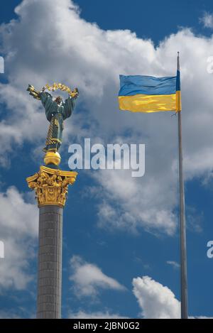 Monumento dell'Indipendenza a Kiev e bandiera ucraina contro il cielo blu con nuvole bianche Foto Stock