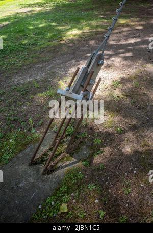 Supporto di albero di filo ancorato nel terreno con calcestruzzo e quattro bulloni nel terreno di parcheggio. Foto Stock