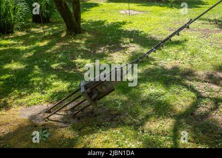 Supporto di albero di filo ancorato nel terreno con calcestruzzo e quattro bulloni nel terreno di parcheggio. Foto Stock