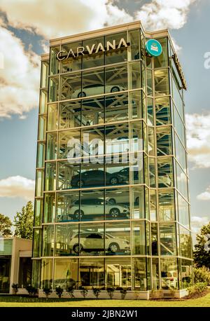 Il distributore automatico di auto a torre di vetro di Carvana è pieno di veicoli in attesa di essere prelevati dagli acquirenti con marchio in cima e cielo parzialmente nuvoloso. Foto Stock