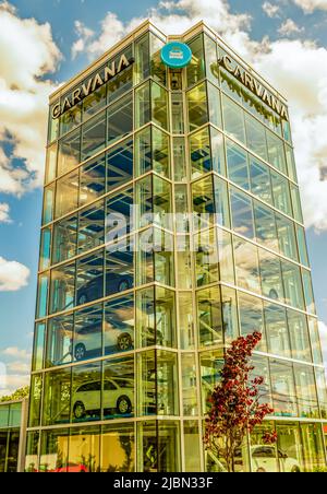 Il distributore automatico di auto a torre di vetro di Carvana è pieno di veicoli in attesa di essere prelevati dagli acquirenti con marchio in cima e cielo parzialmente nuvoloso. Foto Stock