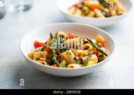 Insalata di pasta con verdure grigliate, zucchine, melanzane, asparagi e pomodori. Foto Stock