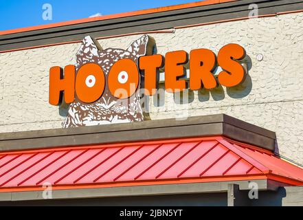 Hoooters Outdoor facciata marchio e logo in grassetto, lettere arancioni sopra una tenda in metallo costolata, su un edificio testurizzato in luce solare brillante. Foto Stock