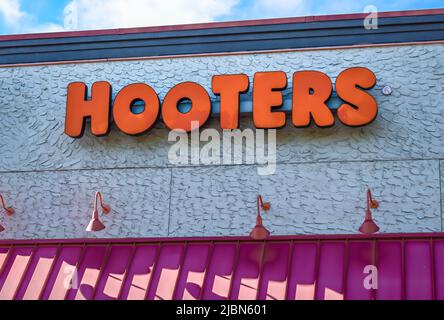 Hoooters Outdoor facciata marchio e logo in grassetto, lettere arancioni sopra una tenda in metallo costolata, su un edificio testurizzato in luce solare brillante. Foto Stock