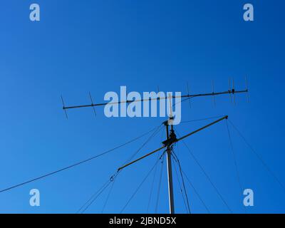 Un'antenna radio VHF con funi di supporto contro il cielo blu Foto Stock