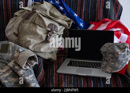 Zaino e laptop contro la bandiera americana. Educazione militare Foto Stock