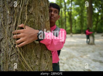 I bambini della scuola di Netaji Subhas Vidyaniketan posano e abbracciano gli alberi per la macchina fotografica nella Giornata Mondiale dell'ambiente. La Giornata Mondiale dell'ambiente si celebra ogni anno il 5th giugno ed è riconosciuta dalle Nazioni Unite per creare consapevolezza e azioni per la protezione dell'ambiente. Agartala, India. Foto Stock