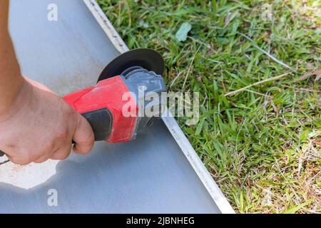 Le mani del lavoratore tagliano una lamiera di metallo Foto Stock