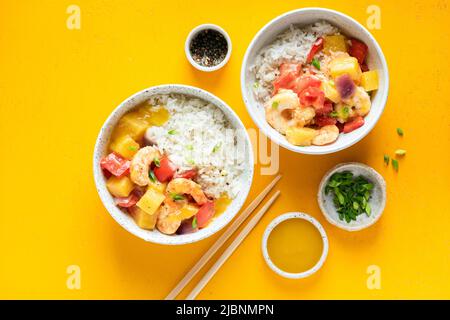 Ananas e gamberi al curry con riso bianco in ciotola su sfondo giallo. Vista dall'alto del tavolo. Cucina asiatica Foto Stock