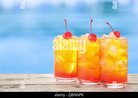 Bicchieri di cocktail Tequila Sunrise freddo sul bordo della piscina Foto Stock