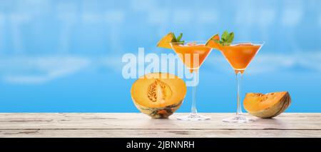 Bicchieri di cocktail di melone freddo sul bordo della piscina Foto Stock