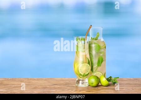 Bicchiere e bottiglia di cocktail mojito freddo sul bordo della piscina Foto Stock