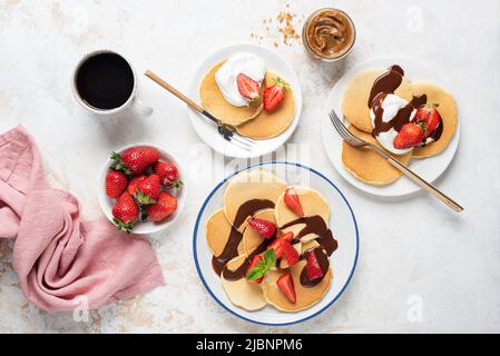 Prima colazione pancake con fragole, yogurt e salsa al cioccolato. Vista dall'alto. Colazione dolce per famiglie con pancake Foto Stock