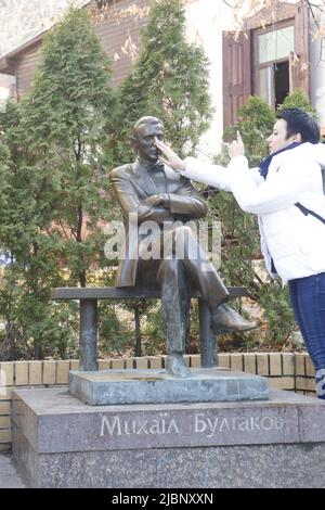 La signora tocca il naso del monumento di Mikhail Bulgakov vicino alla sua casa-museo a Kiev. E 'come una buona fortuna deve fare quando si visita ' Maestro e Margarita' autore Foto Stock