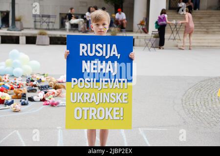 Lubiana, Slovenia. 07th giugno 2022. Un ragazzo porta un cartello con la scritta "Russia, smetta di stuprare i bambini ucraini” durante un raduno europeo per la protezione dei bambini ucraini colpiti dalla guerra in Ucraina. Finora sono stati segnalati oltre 240 bambini uccisi durante la guerra. Credit: SOPA Images Limited/Alamy Live News Foto Stock