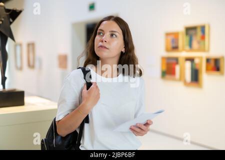 Una ragazza focalizzata visita una mostra in una galleria d'arte Foto Stock