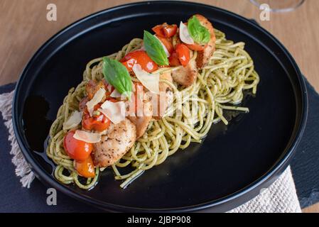 Pomodori ciliegini con pasta di pollo in un piatto nero Foto Stock