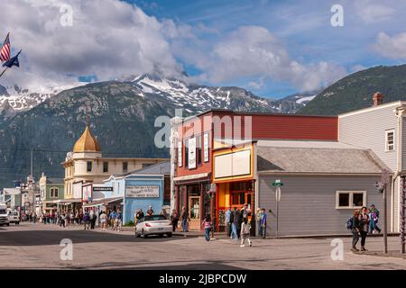 Skagway, Alaska, Stati Uniti d'America - 20 luglio 2011: Negozi al dettaglio a Broadway con Golden North Hotel Tower sul retro sotto il paesaggio blu nuvoloso e la montagna innevata Foto Stock